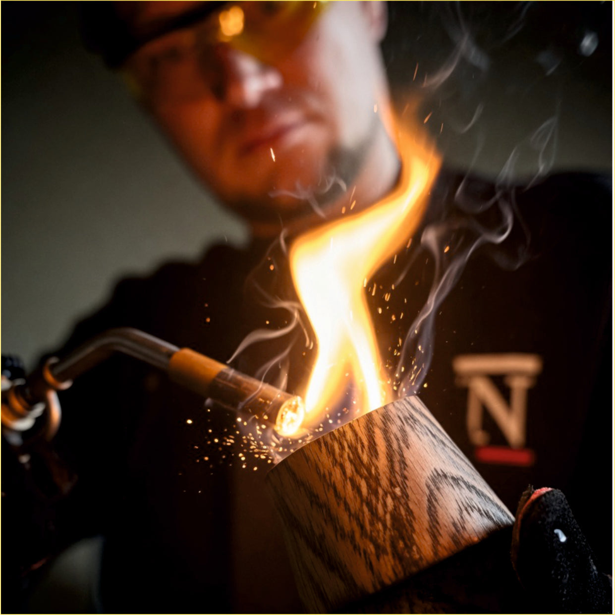 A handcrafted wooden whiskey glass being flame-finished in the AltaadiR family workshop.