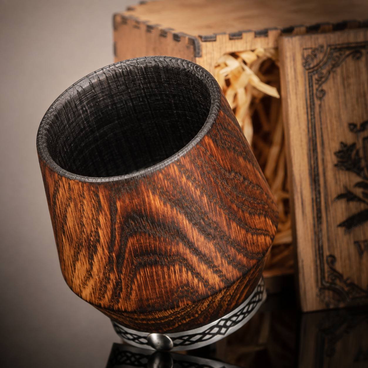 Close-up of the naturally fire-charred interior and distinctive wood grain of a handcrafted oak whiskey glass.