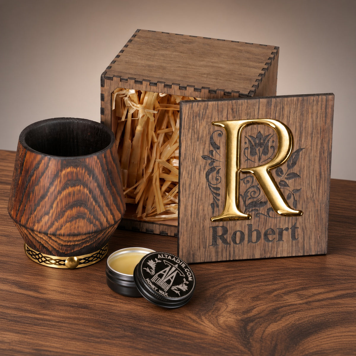 Charred oak whiskey tumbler with a gold-toned base ring, wooden box with a gold R monogram and Robert engraving, and care balm