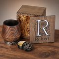 Charred oak whiskey tumbler with a silver base ring, wooden gift box personalized with an R monogram and Robert, and care balm.