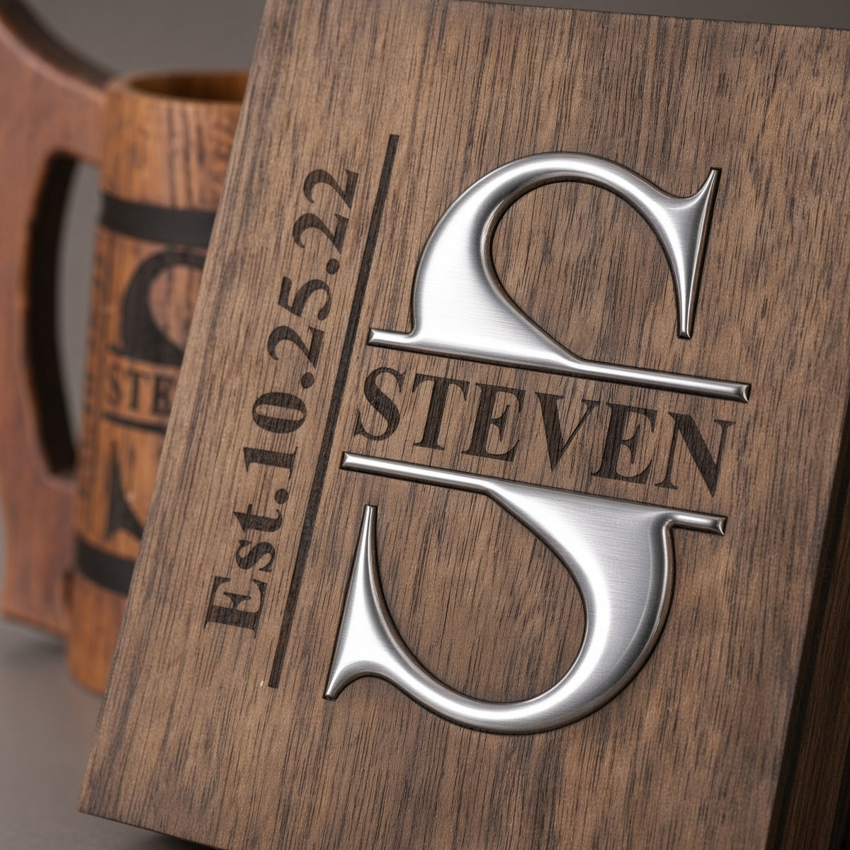 Close-up of a wooden gift box lid with a silver-colored epoxy resin S monogram, engraved Steven name, and date.