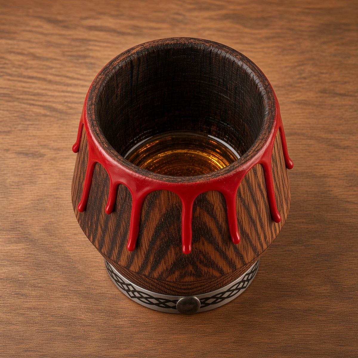 Top view of an oak whiskey glass showing its dark interior and red drip rim on a wooden surface.