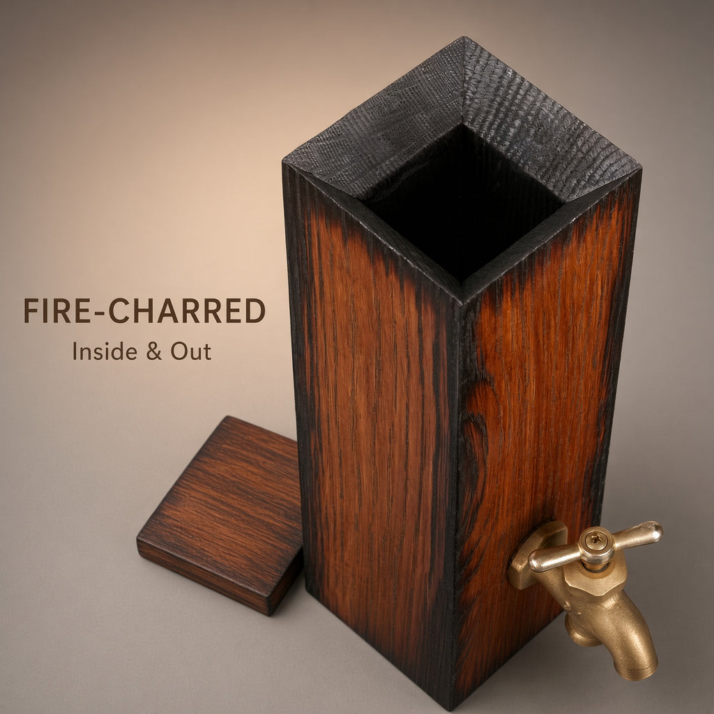 Top view of the open oak whiskey dispenser showing its dark charred interior, textured exterior, and removable lid beside it.