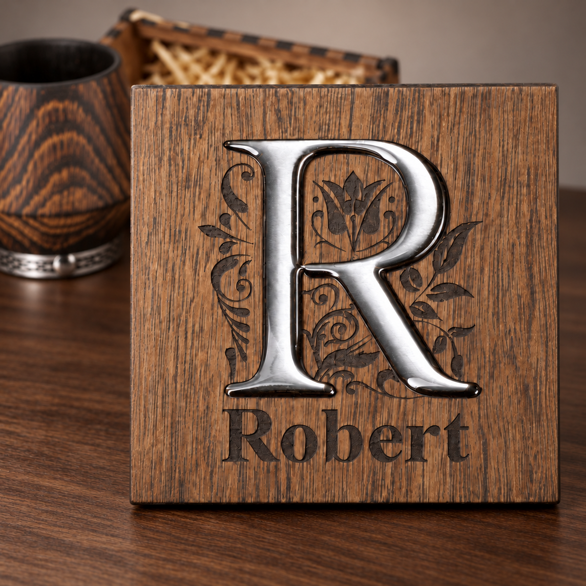 Close-up of a wooden gift box lid with a glossy silver R inlay, floral engraving, and the name Robert.