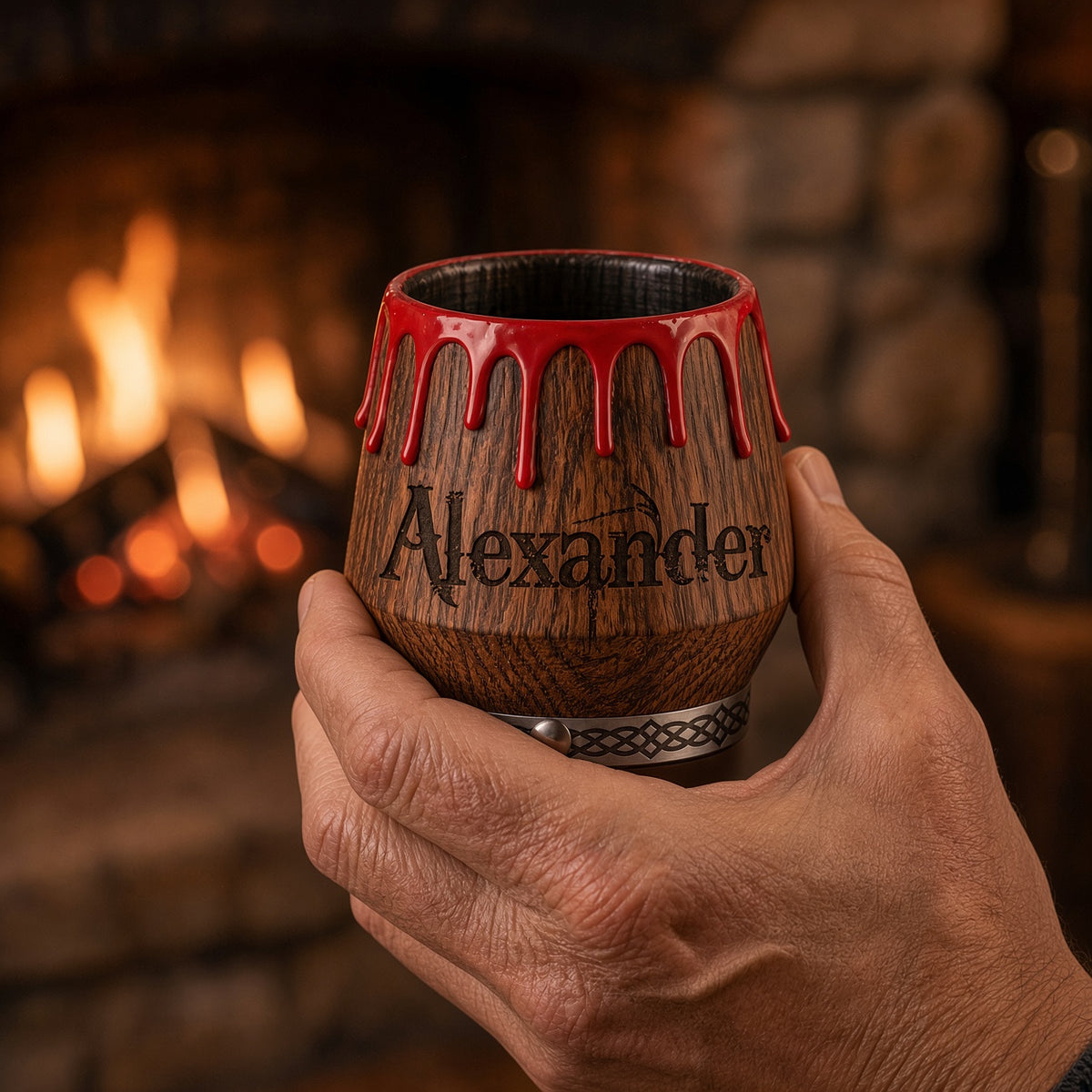 Man holding personalized engraved oak whiskey glass with red drip design in warm home setting