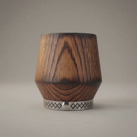Rotating view of a handcrafted charred oak whiskey tumbler with natural wood grain and a decorative metal band