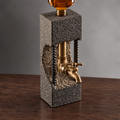 Textured concrete whiskey dispenser with metal tap and exposed steel accents on dark wood surface