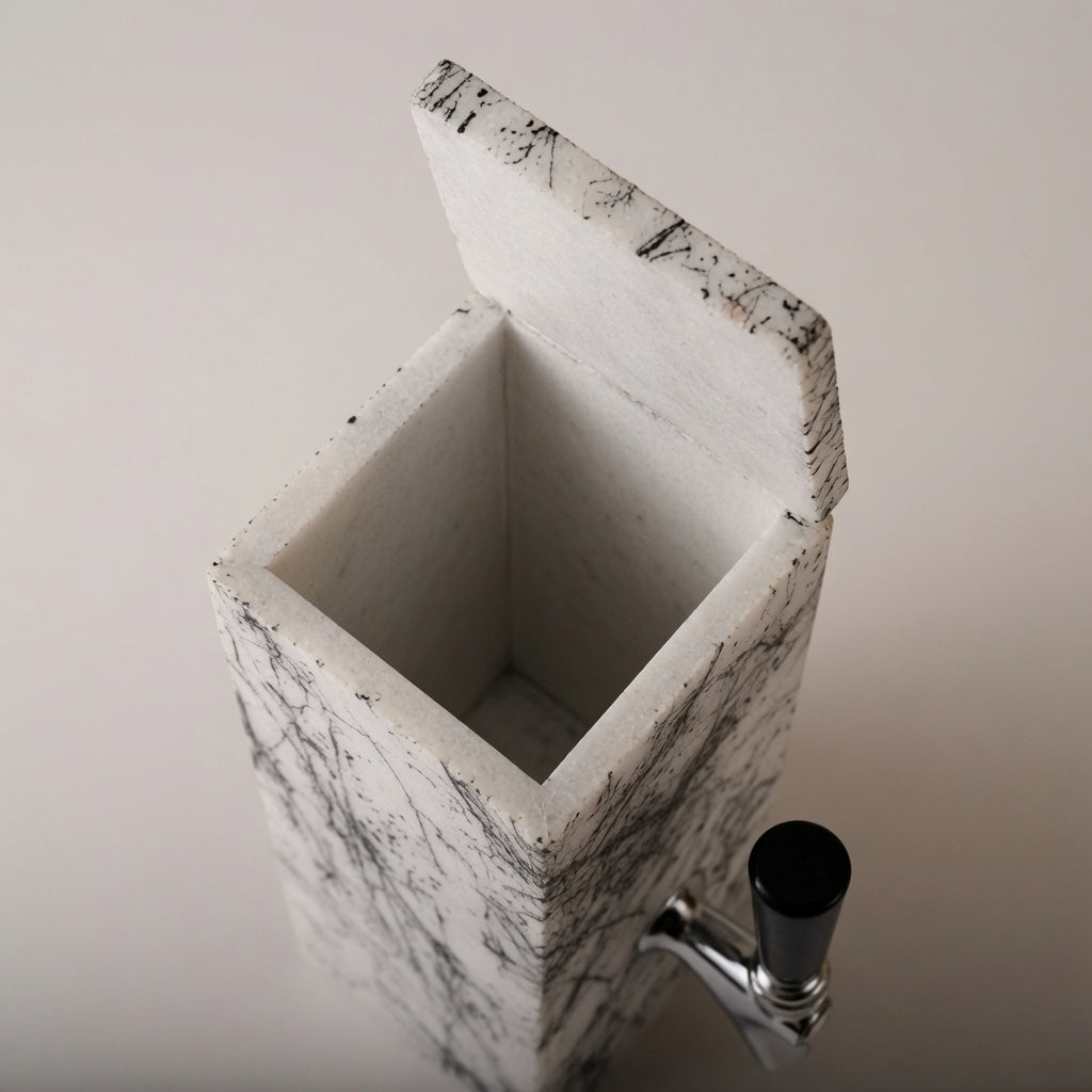 White marble whiskey dispenser with open top showing the inside and hand-decorated black exterior pattern.
